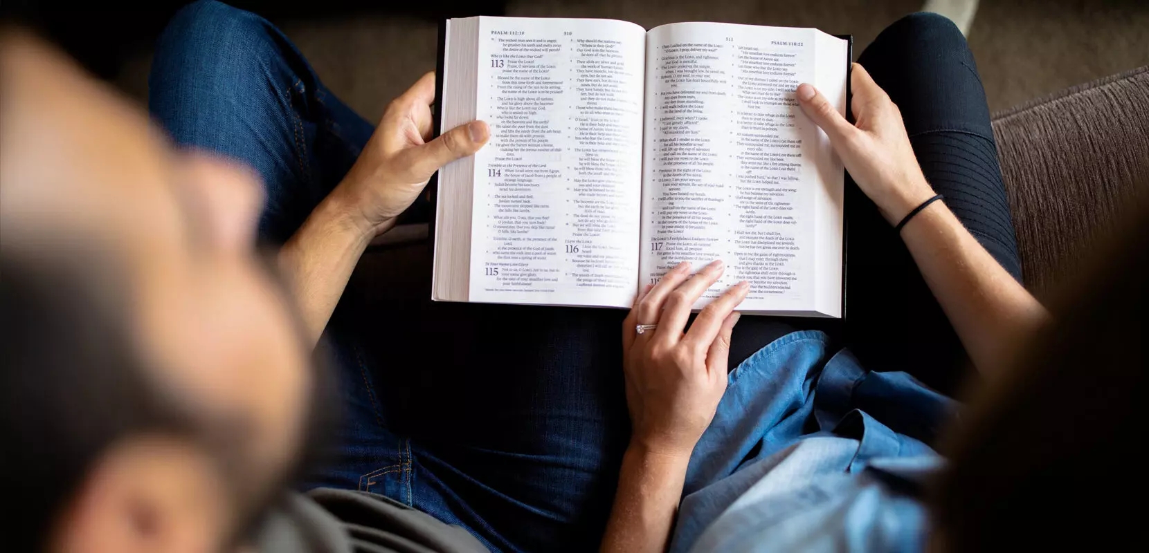 a family sitting on the couch with their bible open