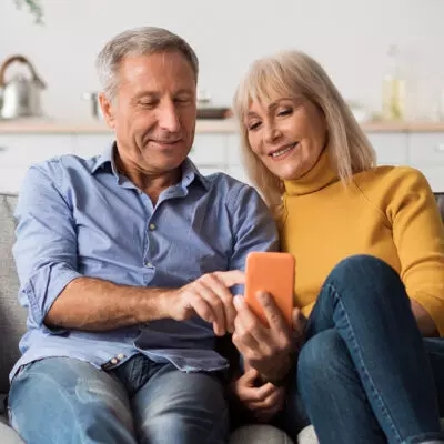 a couple sitting together on a couch and looking at a phone to view their charitable bunching strategy