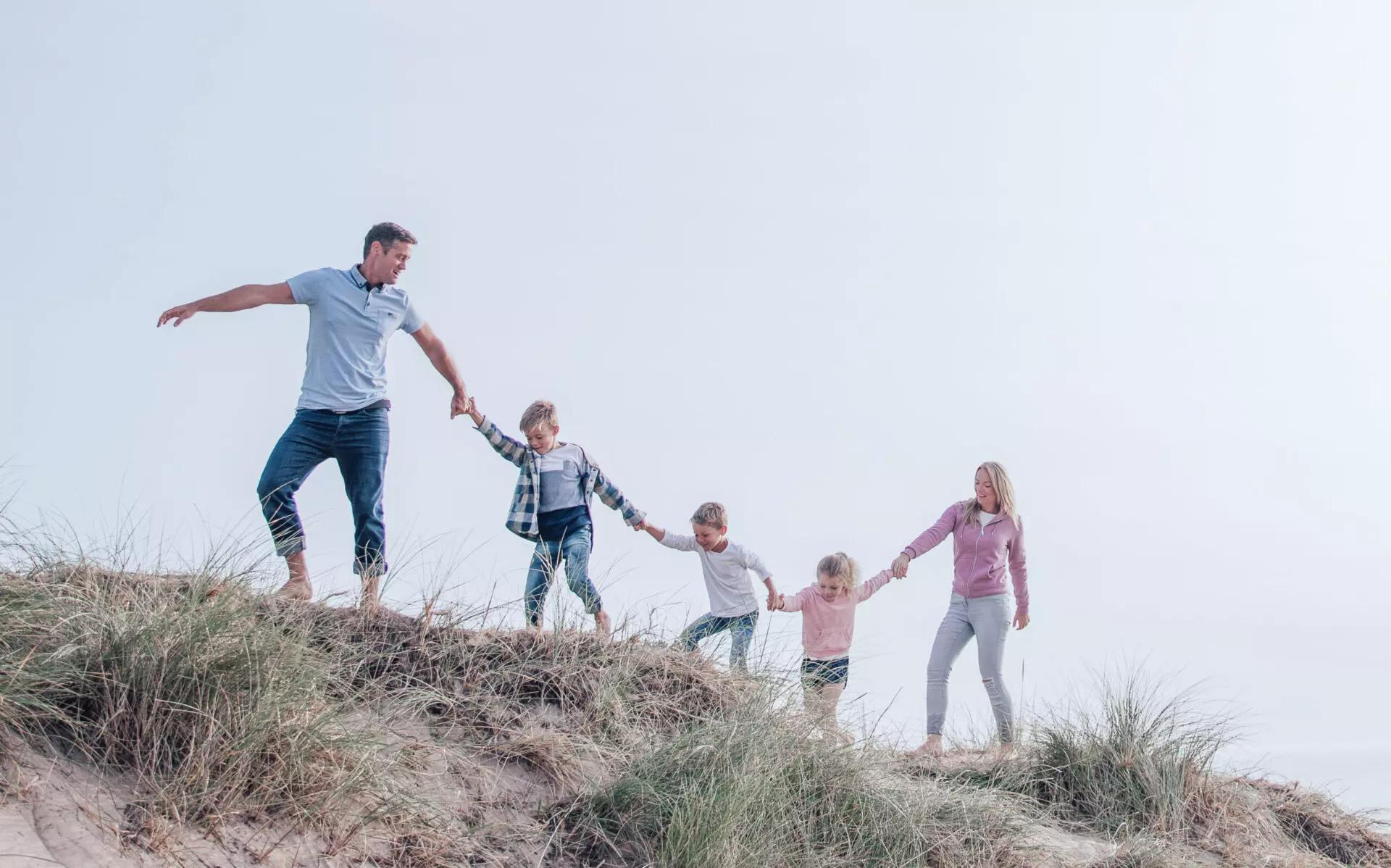 family of five walking along an oceanfront holding hands