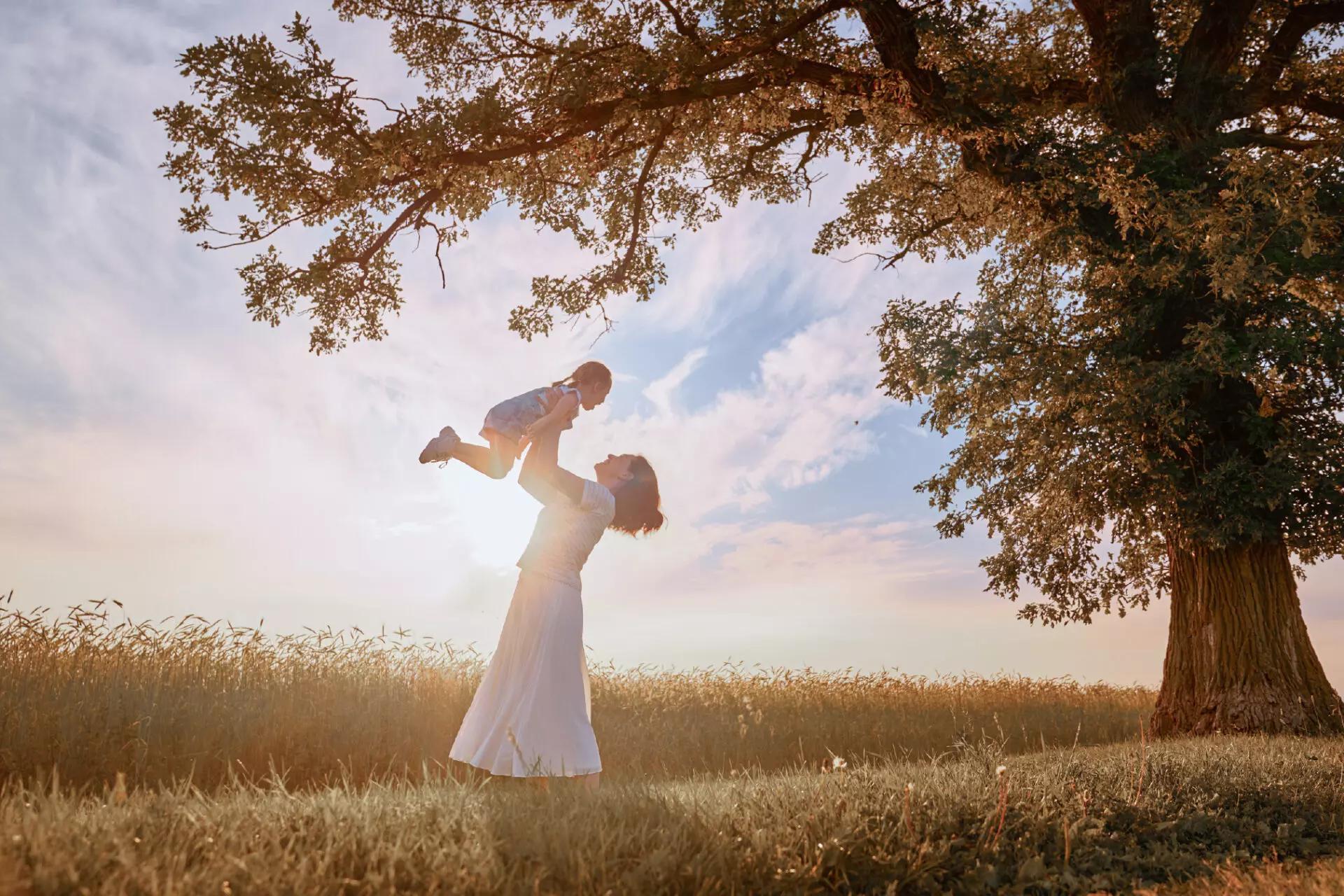 a mother and her child twirling in a field