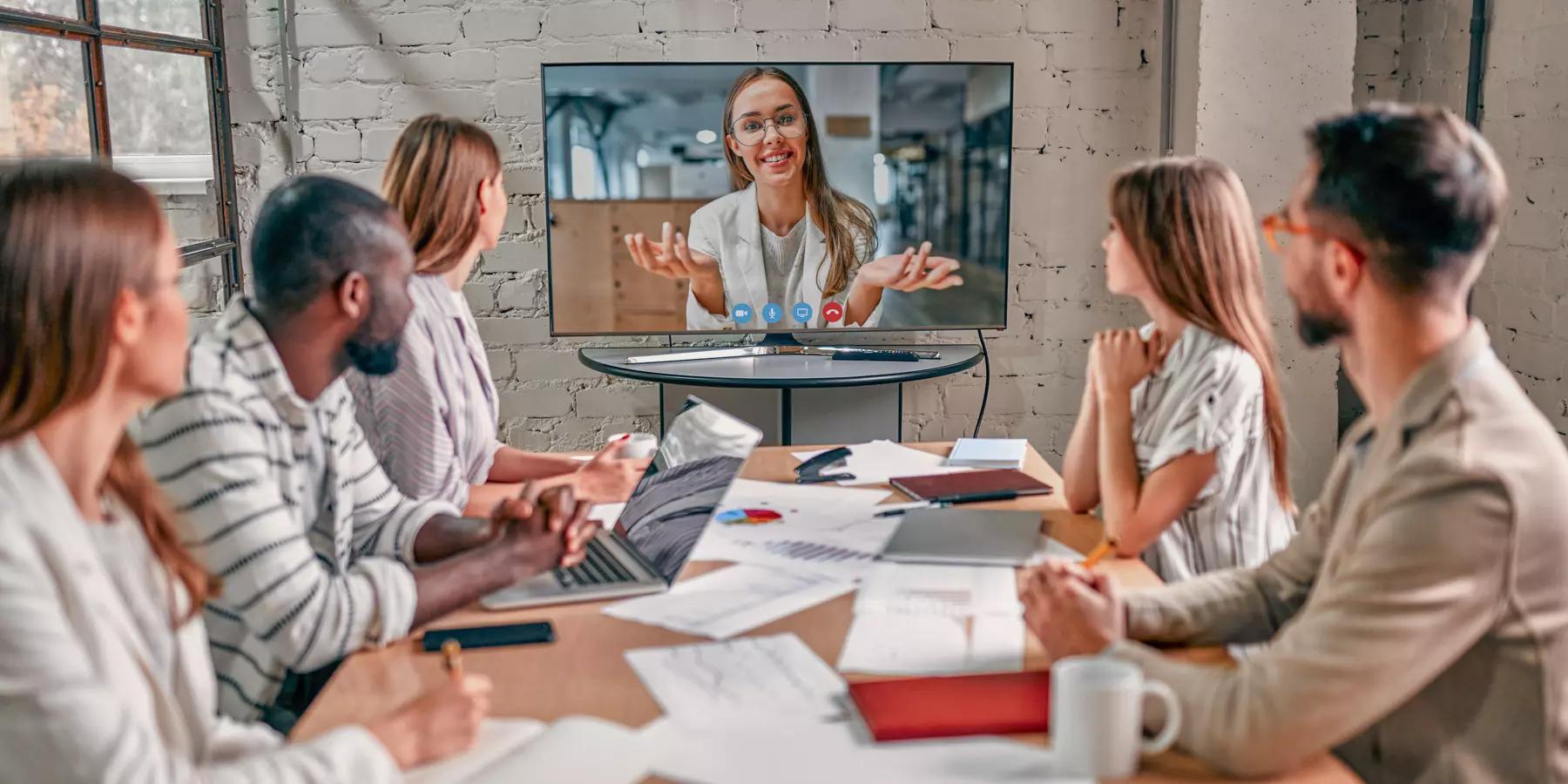 nonprofit video training session with 5 people at a table and one person training via video